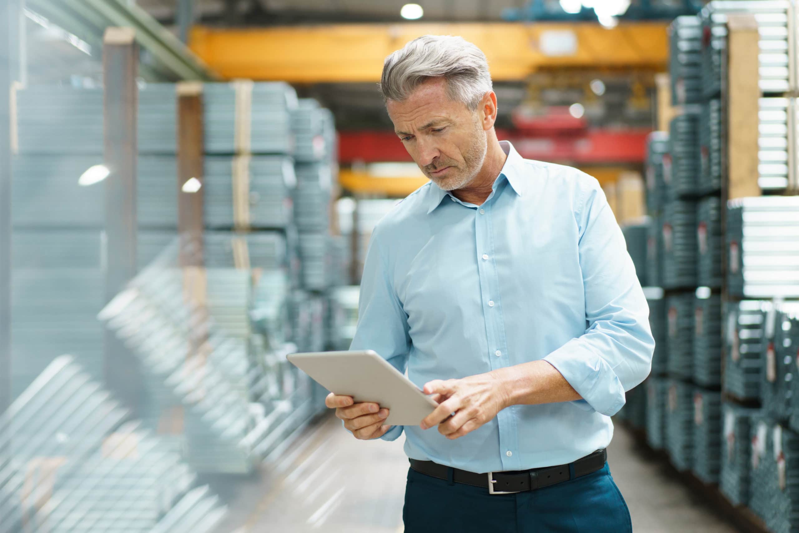 Man in warehouse reading tablet in hand