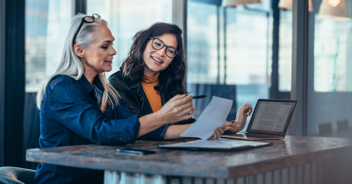 Two women analyzing documents at office