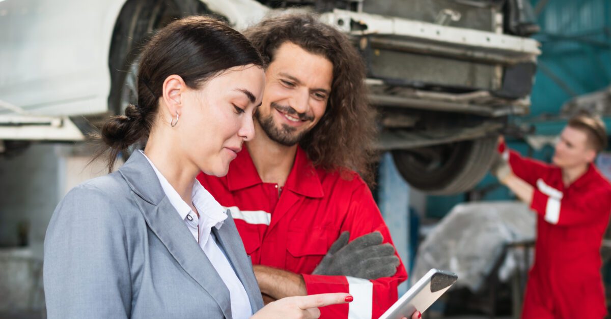 Female manager and car mechanic while working in auto repair shop, Woman at a car garage getting mechanical service, Car repair and maintenance concepts