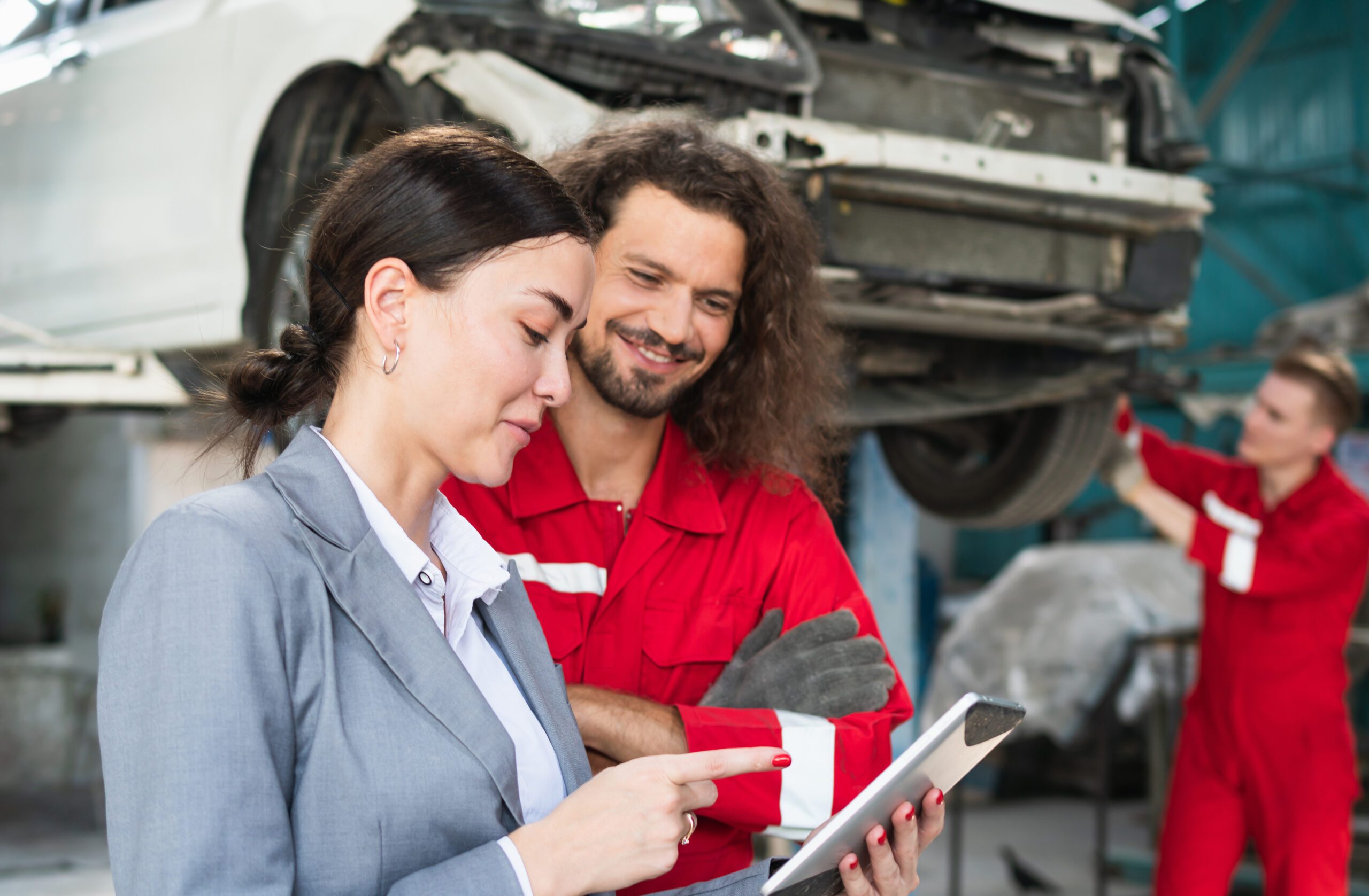 Female manager and car mechanic while working in auto repair shop, Woman at a car garage getting mechanical service, Car repair and maintenance concepts